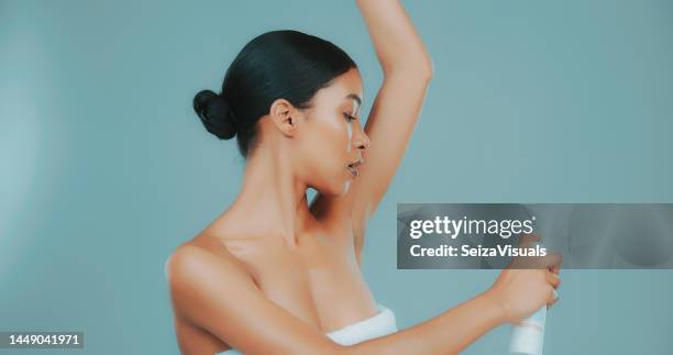 studio shot of woman spraying deodorant on her underarms - armpit stock pictures, royalty-free photos & images