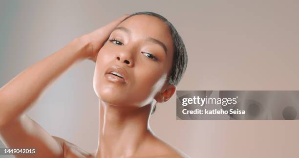 studio shot of attractive woman posing with her hand in hair - studio head shot serious confident looking at camera imagens e fotografias de stock