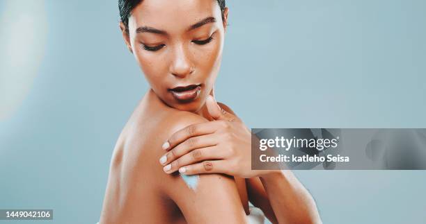 studio shot of attractive woman applying moisturizer on body - face arms stock pictures, royalty-free photos & images