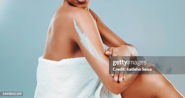 studio shot of woman wrapped in towel applying body lotion - applying sunscreen stock pictures, royalty-free photos & images