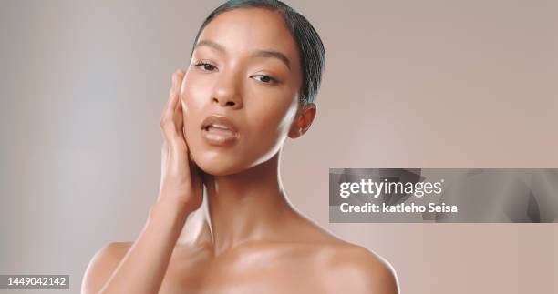 studio shot of beautiful woman touching her glowing face - female model attitude face on stock pictures, royalty-free photos & images