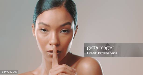 studio shot of female model posing with finger on her lips - studio head shot serious confident looking at camera imagens e fotografias de stock