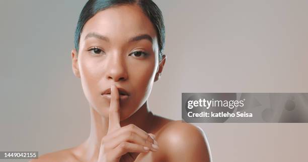 studio shot of confident model posing with finger on lips - woman hush stock pictures, royalty-free photos & images