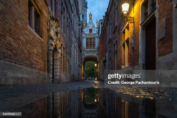 reflections on an alley in the medieval town of bruges, belgium - bruges night stock pictures, royalty-free photos & images