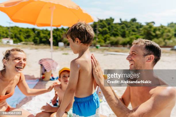 aplicar protector solar mientras está en la playa - toldo fotografías e imágenes de stock