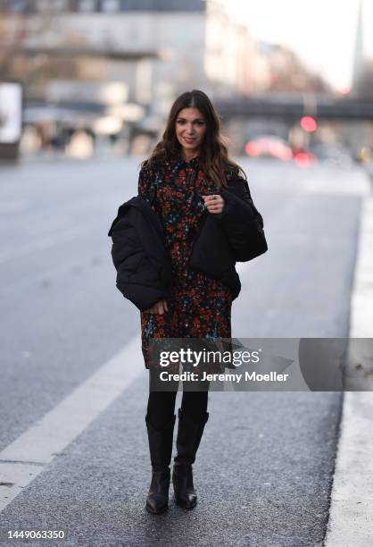 Anna Wolfers seen wearing a red and blue flower printed dress, black tights, black cowboy boots and a dark down jacket on December 09, 2022 in...