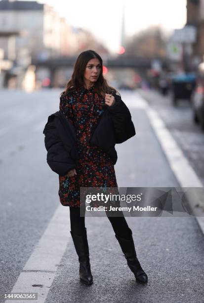 Anna Wolfers seen wearing a red and blue flower printed dress, black tights, black cowboy boots and a dark down jacket on December 09, 2022 in...