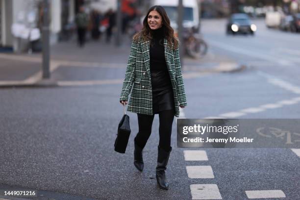 Anna Wolfers seen wearing a green patterned blazer jacket, a black leather mini skirt, dark tights, a black turtle neck sweater, black cowboy boots...