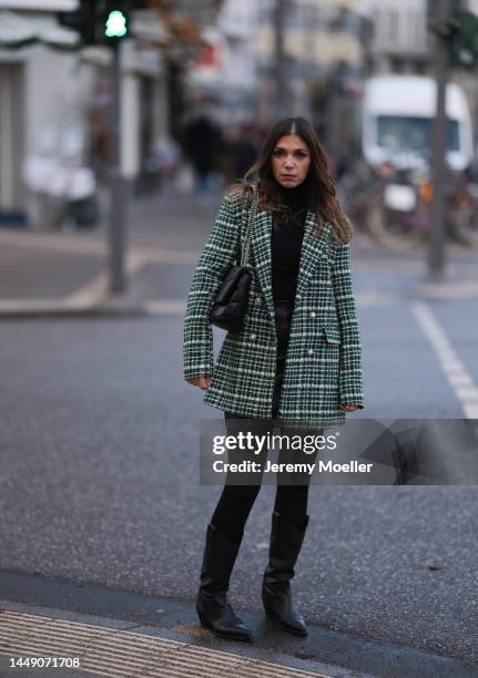 Anna Wolfers seen wearing a green patterned blazer jacket, a black leather mini skirt, dark tights, a black turtle neck sweater, black cowboy boots...