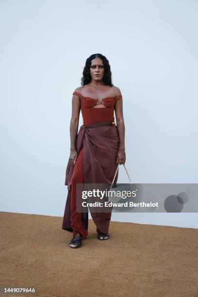 Guest wears a red brown V-neck / cut-out chest / sleeveless body top, matching red brown large pants, a brown wrap long skirt, a white shiny leather...