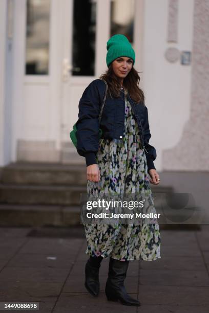 Anna Wolfers seen wearing a long green patterned wide dress, a green bag, a matching green beanie, black cowboy boots and a bomber jacket on December...