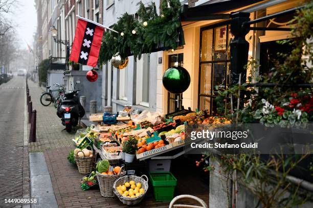 General view of Fruit and vegetable shop with the flag of Amsterdam displayed on Jordaan District on December 10, 2022 in Amsterdam, Netherlands....