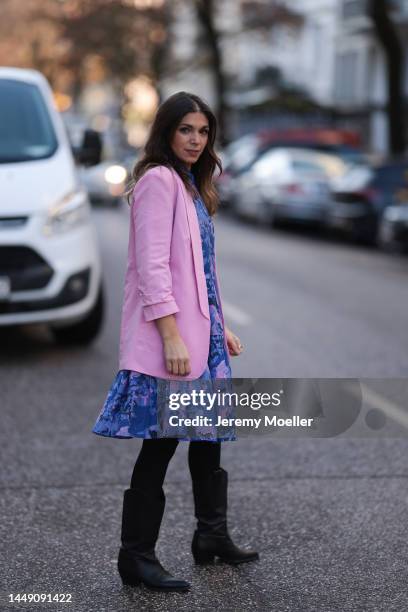 Anna Wolfers seen wearing an oversized blue and pink patterned flower dress, black cowboy boots and a light pink blazer on December 09, 2022 in...