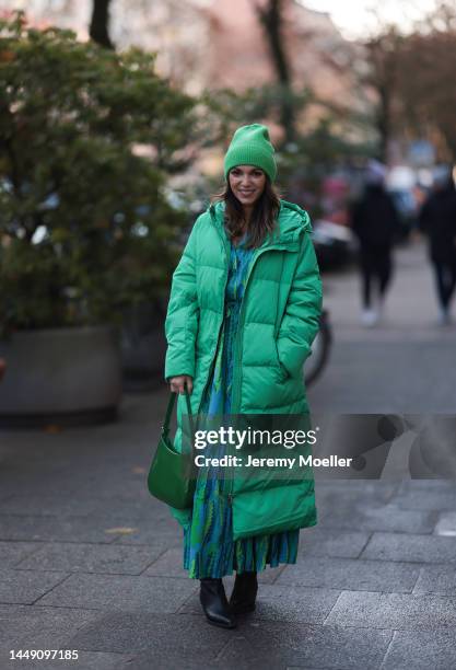 Anna Wolfers seen wearing a green patterned long dress, a green long down coat, a matching green beanie, a green bag and black boots on December 09,...