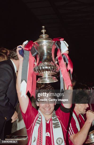 Bryan Robson of Manchester United holds the trophy aloft after their victory in the FA Cup final replay against Crystal Palace at Wembley Stadium on...