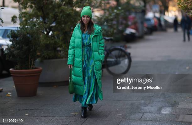 Anna Wolfers seen wearing a green patterned long dress, a green long down coat, a matching green beanie, a green bag and black boots on December 09,...