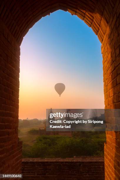 the frame of the old bagan pagoda with hot air balloons flying in the background - theravada stock pictures, royalty-free photos & images
