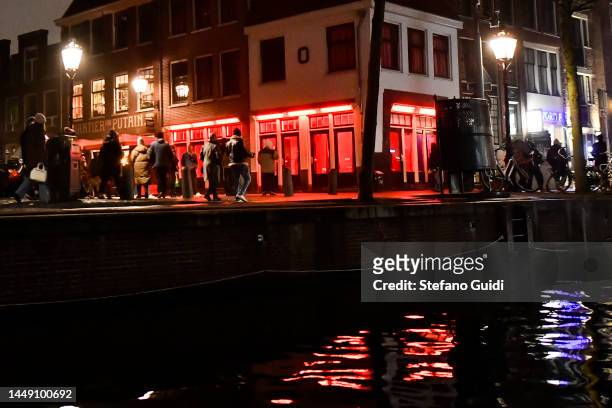 People walks near of red Light inside the Red Light District on December 10, 2022 in Amsterdam, Netherlands.De Wallen, Amsterdam's red-light...