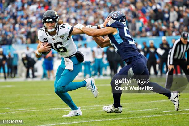 Trevor Lawrence of the Jacksonville Jaguars avoids the tackle of Dylan Cole of the Tennessee Titans and runs for a touchdown at Nissan Stadium on...