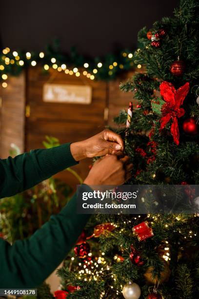 giovane donna felice che decora l'albero di natale nel suo soggiorno - decorare l'albero di natale foto e immagini stock