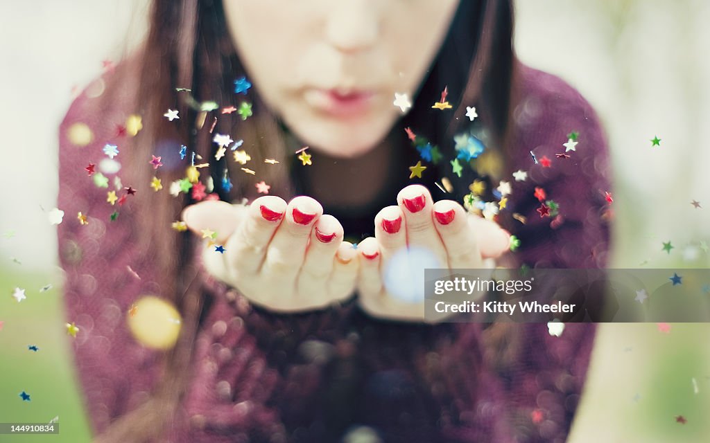 Young woman blowing star confetti