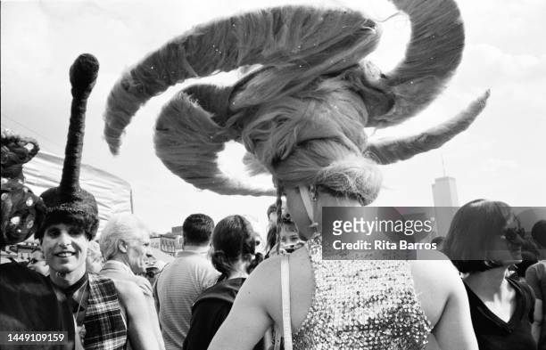 View, from behind, of an attendee with a large headpiece during Wigstock, an annual drag festival, in Tompkins Square Park, New York, New York,...