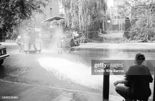 View of children as they play with water from an open hydrant on the Lower East Side, New York, New York, June 2, 1998.