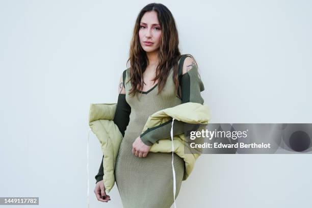 Guest wears a khaki V-neck / long sleeves / cut-out shoulder / long wool tube dress, a pale green sleeveless puffer jacket, outside the "Le Raphia"...