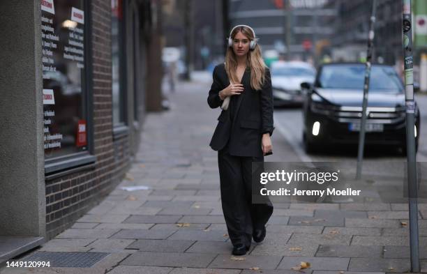 Christina Adler seen wearing white JBL headphones, black striped suit gilet, matching black striped blazer jacket and black striped suit pants, black...