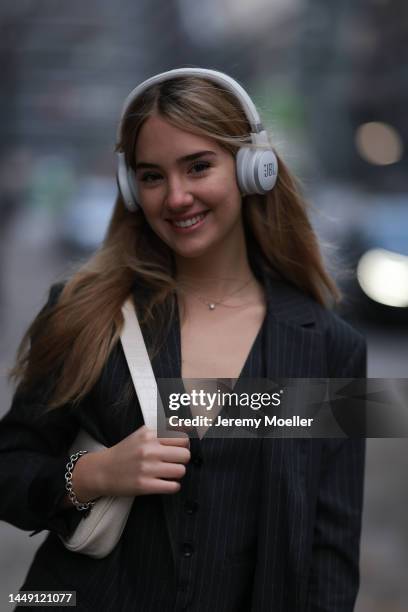 Christina Adler seen wearing white JBL headphones, black striped suit gilet, matching black striped blazer jacket and black striped suit pants and a...