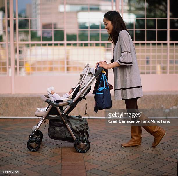 mother pushing baby in stroller - ベビーカー ストックフォトと画像