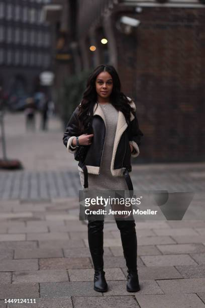 Justine Quansah seen wearing beige short knit dress, gold necklace, dark brown leather jacket, black leather high boots and Valentino black studded...