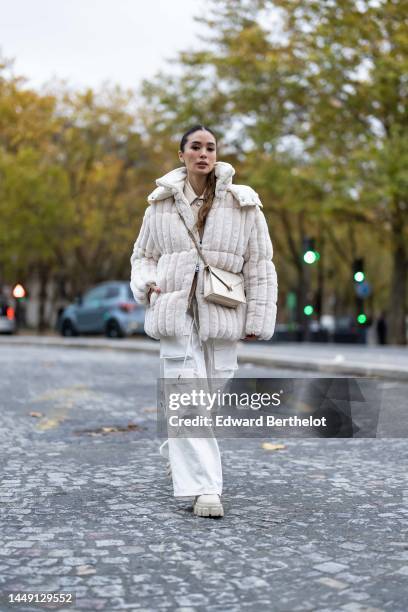 Heart Evangelista wears diamonds earrings, a beige shiny leather shirt, a white latte embossed striped print pattern fur oversized zipper coat, a...