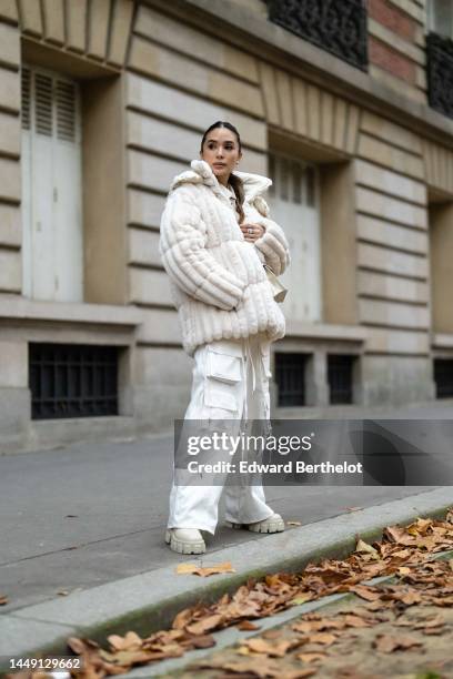 Heart Evangelista wears diamonds earrings, a beige shiny leather shirt, a white latte embossed striped print pattern fur oversized zipper coat, a...