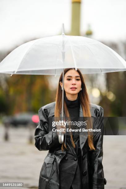 Heart Evangelista wears diamonds earrings, a black turtleneck pullover, a black shiny leather buttoned blazer jacket, a black shiny leather oversized...