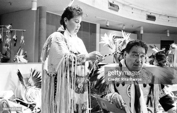 View of an unidentified performer as she braids a fellow performer's hair, both in traditional clothing, as they prepare before a Tuscarora Indian...