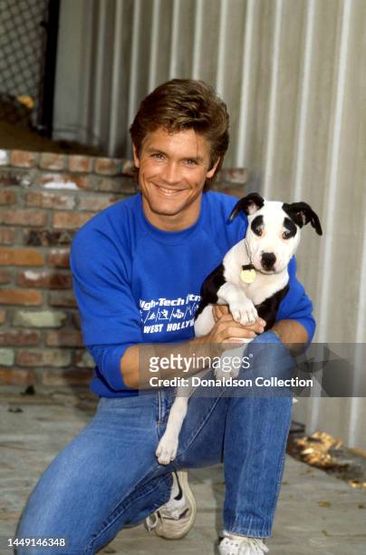American executive, film producer, director and actor Andrew Stevens poses for a portrait with his dog, Los Angeles, California, circa 1985.