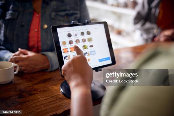 employee uses point of sale app on tablet - poes stock-fotos und bilder