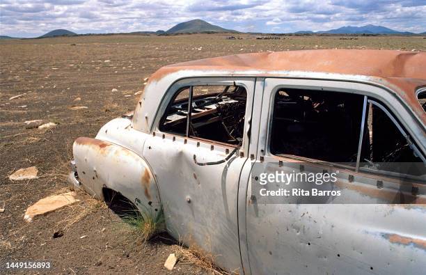 View of an abandoned car, pockmarked with holes, in the desert, Arizona, August 2006.