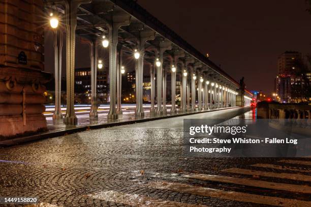 time exposure with light trails from traffic passing across the bir-hakeim bridge at night after an evening rain with pedestrian crosswalk in foreground - railway bridge stock-fotos und bilder