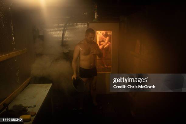 Member of the Ukrainian military reacts after tipping cold water over himself while relaxing in a makeshift sauna built by members of the brigade in...