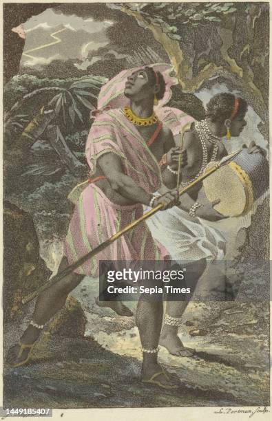 Man and woman are on their way to others to perform a war dance. The woman is holding a war drum and the man his spear. They are wearing traditional...
