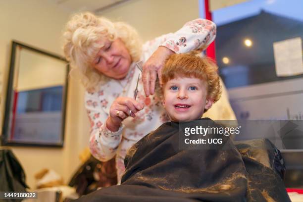 Young boy having a his hair cut at the hairdresser, UK.
