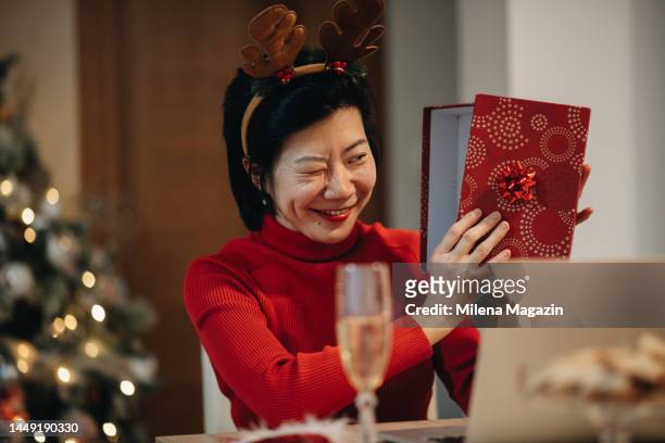 asian woman checking what she got for the holidays - chinese new year dog stock pictures, royalty-free photos & images