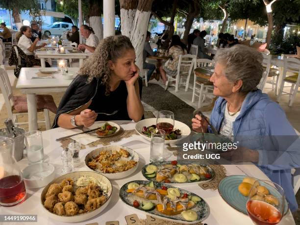 Malia, Crete, Greece, Two women enjoying a selection of starters during supper in a Greek restaurant.