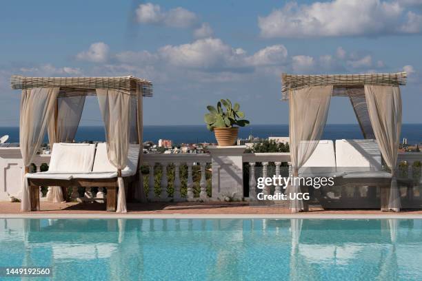 Crete, Greece, Sunbeds with drapes and mattress for two siuated around a swimming pool.