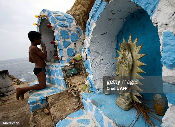 Bryant Ramirez, a 14 year-old cliff diver, prays in front of the image of the Guadalupe Virgin, before jumping at La Quebrada in Acapulco, Mexico on...