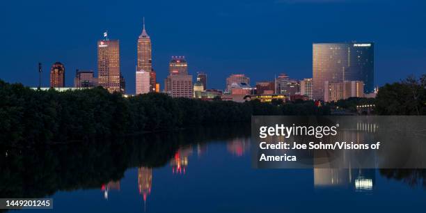 Skyline view at sunset into dusk of Indianapolis buildings on White River reflect in water, Indiana.