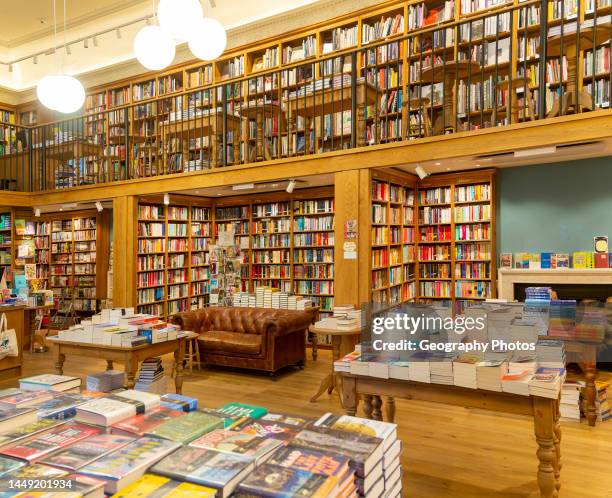 Bookshelves and piles of books, Topping and Company booksellers shop, Bath, Somerset, England, UK.