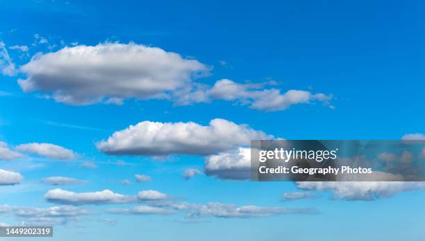 Layers of white fluffy cumulus clouds in blue sky, Suffolk, England, UK.